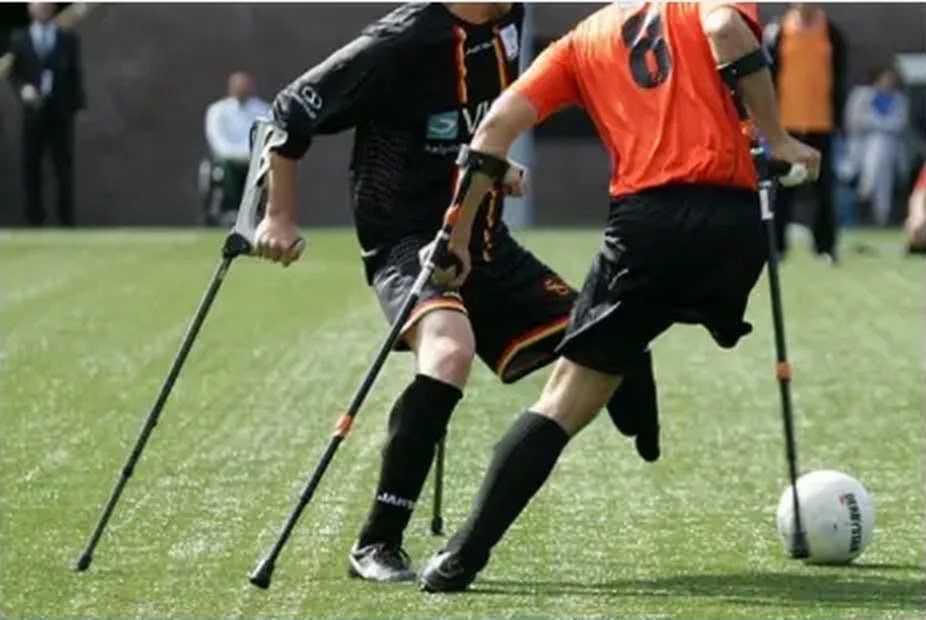 Amputee footballers using forearm crutches competing for the ball on a pitch