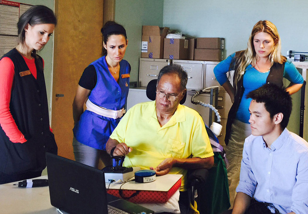 A person learning to use assistive technology with two ATRC staff members