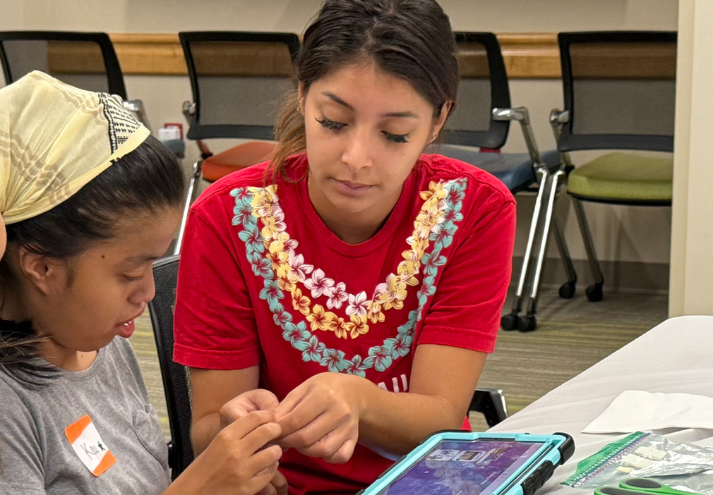 A woman showing a girl how to use an assistive technology device