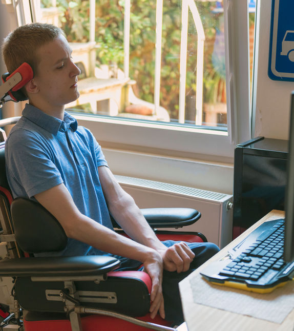 A young man using a wheelchair while working at a computer