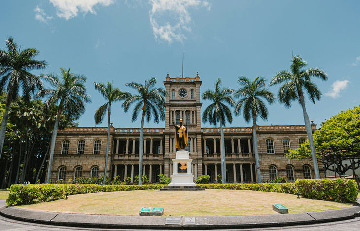 Aliʻiōlani Hale in Honolulu with the King Kamehameha statue and palm trees
